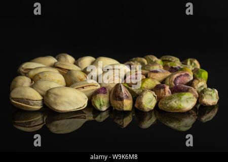 Sacco di tutto mature pistacchio verde metà è senza guscio isolato sul vetro nero Foto Stock