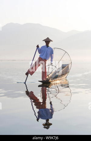 Intha "gamba" a remi dei pescatori al tramonto sul Lago Inle che pescano con reti tesa su conica telai di bambù, Lago Inle, Myanmar Foto Stock