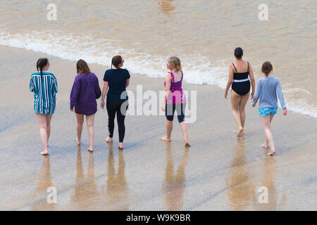 Un gruppo di turisti femmina camminando lungo la riva a grande Gt. Western Beach in Newquay in Cornovaglia. Foto Stock