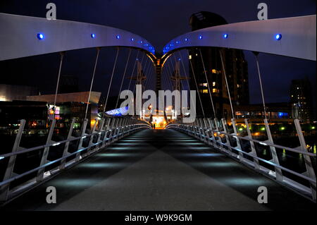 Vista notturna di The Lowry ponte sopra il Manchester Ship Canal, Salford Quays, Greater Manchester, Inghilterra, Regno Unito, Europa Foto Stock