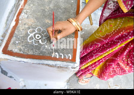 Pittura di donna di casa sua con farina di riso pasta, rendendo rangoli design Festival Diwali decorazioni, Udaipur, Rajasthan, India Foto Stock