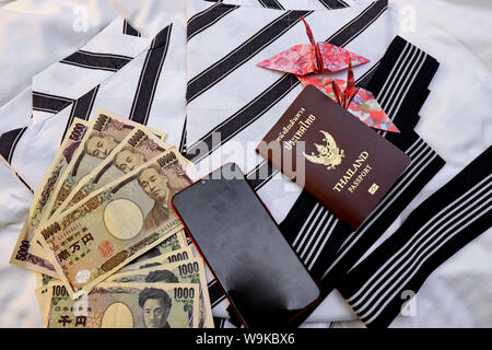 Passaporto,telefono mobile,soldi banconote, carte di credito e carta origami uccelli posto sul giapponese pigiami chiamata come uno yukata Foto Stock