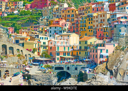 Manarola, La Spezia, Italia - Luglio 2, 2019: Waterfront con case colorate e la gente a piedi a Manarola piccola cittadina sulla soleggiata giornata estiva, Cinque Terr Foto Stock