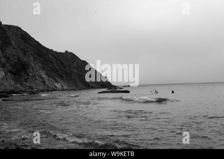 Punto Arena, CA - Agosto 3, 2019: Surfers sit out in the cove in attesa di onde Foto Stock