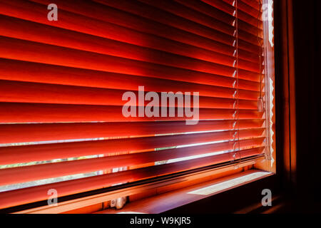 Chiusura in plastica arancione persiane con la luce del sole di mattina. finestre con persiane. Il design degli interni di soggiorno con finestra tende orizzontali.CHIUSO Foto Stock