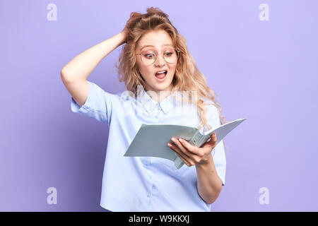 Perplesso funny studente è espressione contemplativa, detiene il notebook dai graffi con testa handl, profondo in pensieri, ha problemswith memoria, non è in grado di Foto Stock