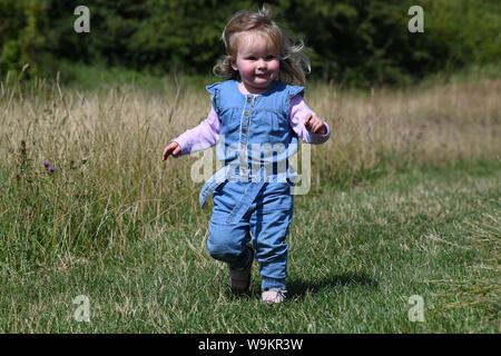 Bimbo bimba in esecuzione in erba prato Regno Unito Foto Stock