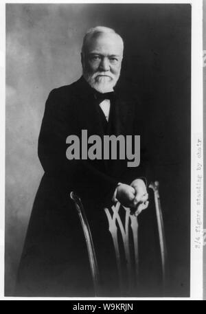 Andrew Carnegie, tre quarti di lunghezza verticale, in piedi dietro la sedia, rivolto verso la parte anteriore Foto Stock