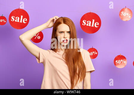 Perplesso sorpreso donna graffiare la sua testa, pensando a la sua giornata di shopping, pianificare il suo weekend. problema. ragazza non hanno molto denaro per comprare un panno Foto Stock