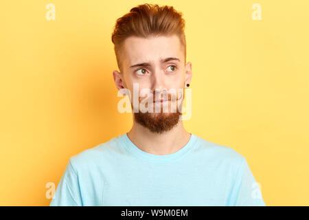 Close up ritratto. pensieroso giovane uomo bello guardare lontano, cercando di ricordare alcune informazioni isolati a sfondo giallo, studio shot Foto Stock