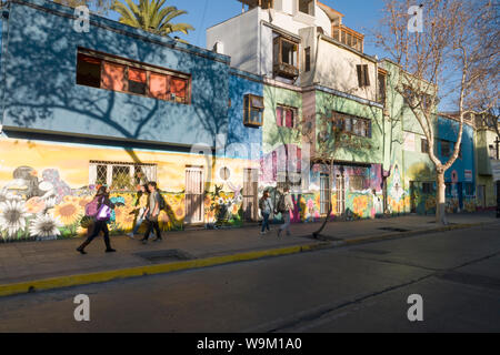 I pedoni a piedi passato murales su edifici in legno in Bellavista, Santiago del Cile Foto Stock