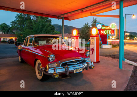 Vista del tramonto di 1955 Studebaker Presidente classico auto parcheggiata di fronte antichi pompe per gas convertito in elettrico auto caricabatterie; il cerchio R Motel; Salida Foto Stock