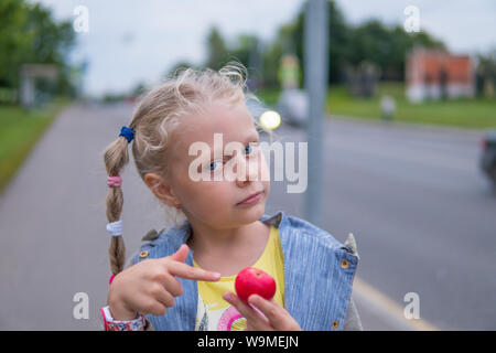 Ragazza con pig-tail mangia la mela rossa, funy Foto Stock