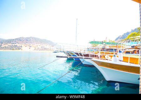 Numerosi yacht ormeggiati nel porto contro lo sfondo delle montagne. L'acqua è molto chiaro e blu. Foto Stock