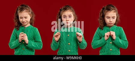 Ritratto di una bellissima bambina in una verde felpa lavorata a maglia in posa su uno sfondo di colore rosso. Foto Stock