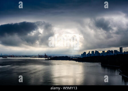 Rottura sole attraverso le nuvole scure in drammatico contrasto elevato sopra Vancouver, British Columbia, Canada. Foto Stock