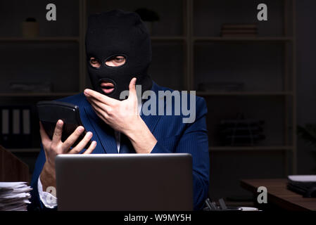 Il dipendente di sesso maschile di rubare informazioni in ufficio tempo di notte Foto Stock