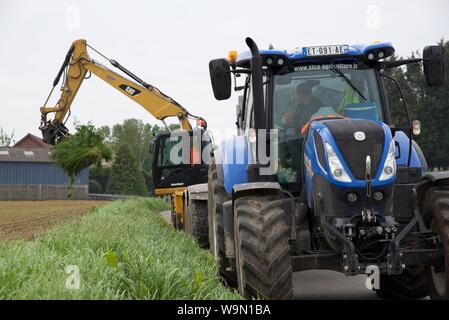 Un trattore e rimorchio escavatore e allineati per scavare e rimuovere il bottino di terra dall'orlo per consentire il montaggio di una tempesta svuotare Foto Stock