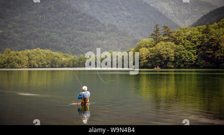 Un pescatore a mosca getta la sua linea in Yunoko o Yuno lago, vicino a Nikko, Giappone. Foto Stock