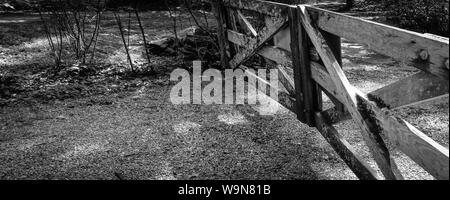 Vecchi cancelli in legno con leichen e alghe chiudere un ingresso lungo una vecchia strada di campagna nel sud-est USA, in bianco e nero Foto Stock