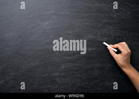 Istruzione o torna al concetto di scuola. Donna mano azienda chalk su lavagna sfondo. Foto Stock