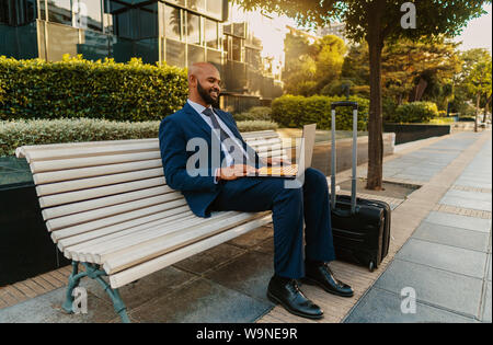 Commerciante indiano holding laptop notebook indossare tuta blu nei pressi di office Foto Stock