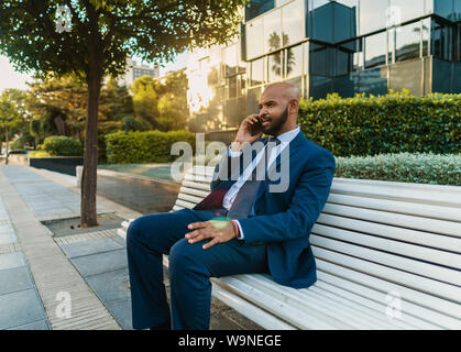 Commerciante indiano tenendo il telefono cellulare da indossare tuta blu Foto Stock