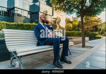 Commerciante indiano tenendo il telefono cellulare da indossare tuta blu Foto Stock