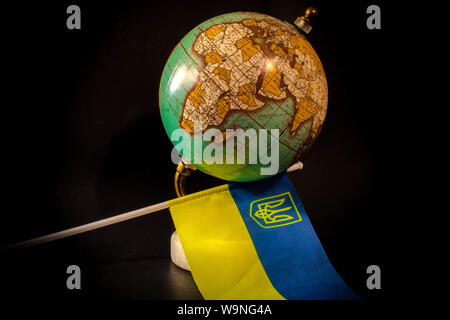 Globo di antiquariato con un titolare di oro e marmo stand , closeup , studiowork , sfondo nero e bandiera ucraino sotto globe Foto Stock