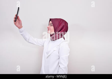 Donna musulmana tenendo ritratto selfie, ragazza in hijab e lei prendendo selfie con telefono mobile Foto Stock