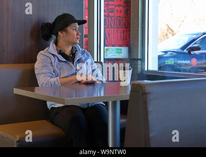 Middletown, CT, Stati Uniti d'America. Apr 2019. Un fuori orario dipendente seduto con pensieri profondi guardando attraverso la finestra. Foto Stock