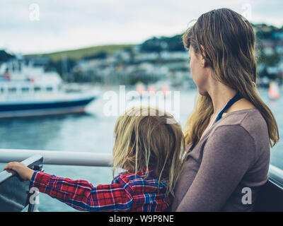 Una giovane madre e il suo bambino sono seduti su una barca in porto Foto Stock