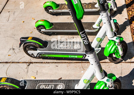 Agosto 14, 2019 San Jose / CA / STATI UNITI D'AMERICA - Lime scooter elettrici parcheggiata vicino a un pubblico centro di transito al fine di coprire l'ultimo miglio; calce è il marchio na Foto Stock