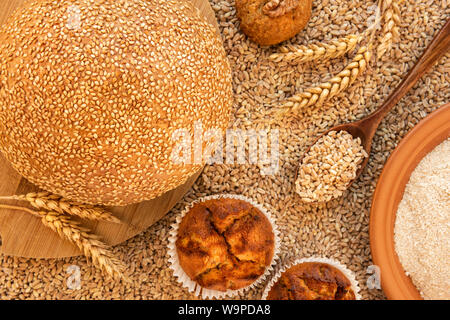 Ancora in vita di pane, muffin, cookie spikelets, una piastra di farina di farro e un cucchiaio riempita di grani. È contro lo sfondo di sparse gr Foto Stock