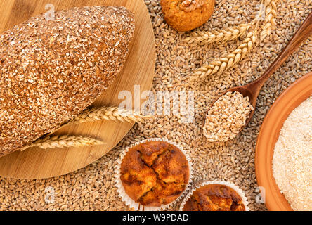 Ancora in vita di pane, muffin, cookie spikelets, una piastra di farina di farro e un cucchiaio riempita di grani. È contro lo sfondo di sparse gr Foto Stock