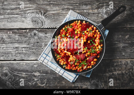 Garbanzos fritos, ceci fritte con chorizo, prosciutto e spezie in una padella, vista orizzontale dal di sopra, piana, laici close-up Foto Stock