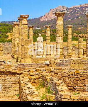 Resti della Basilica principale e la statua dell'Imperatore Traiano in Baelo Claudia sito archeologico. Tarifa, Cadice. Andalusia, Spagna. Foto Stock