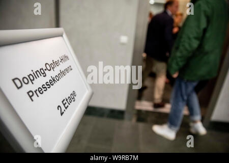 Berlino, Germania. Il 15 agosto, 2019. I partecipanti di una conferenza stampa della associazione Doping-Opfer-Hilfe (DOH) entrare in un ascensore dietro un cartello per la conferenza stampa. Credito: Christoph Soeder/dpa/Alamy Live News Foto Stock