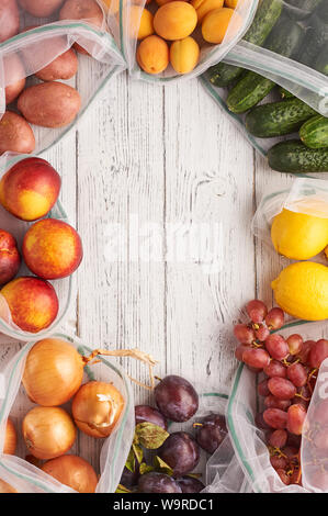 Telaio della frutta e verdura in eco riutilizzabile dei sacchi in bianco sullo sfondo di legno. Sacchetti riciclati invece di sacchetti di plastica. Libero di plastica. Verticale. Top vie Foto Stock