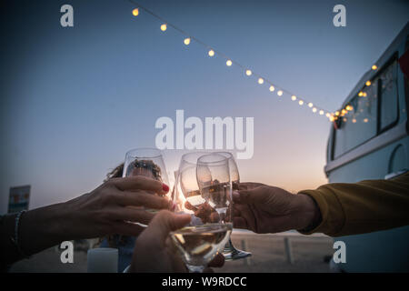 Happy amici tifo e bere il vino durante la vacanza in campeggio in spiaggia con van vintage. Le persone aventi il divertimento a fine settimana serata estiva con campe Foto Stock