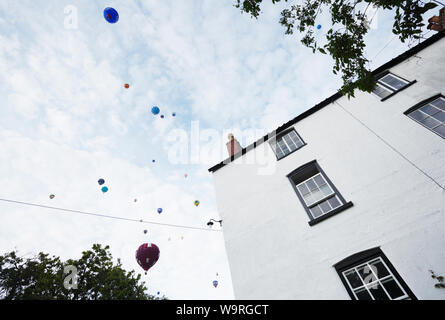Parere conforme di massa di aria calda Mongolfiere sopra casa residenziale in Bristol. Bristol International Balloon Fiesta. Foto Stock