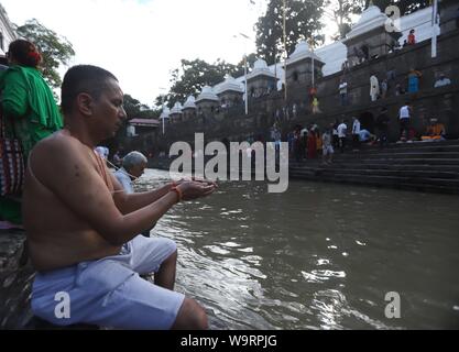 Kathmandu, Nepal. Il 15 agosto, 2019. Devoto nepalese offrendo la preghiera rituale durante Janai Purnima festival o Rakchhya Bandhan al tempio di Pashupatinath, Kathmandu, Nepal, giovedì 15 agosto, 2019. Janai Purnima, noto anche come il filetto sacred festival o Rakshya Bandhan festival indù, gli uomini, specialmente i Brahmans e Chettris, eseguire la loro variazione annua di Janai, sacro fili usurati lungo il petto o legato attorno al polso. Purificato mediante i mantra, il thread è un simbolo di protezione, secondo la credenza indù. Credito: Pacific Press Agency/Alamy Live News Foto Stock