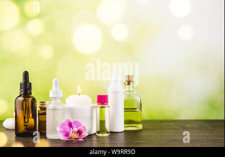 Composizione con sacco di diverse dimensioni, forma e bellezza materiale prodotti cosmetici bottiglie disposizione sul tavolo di legno con verde bokeh studio backg Foto Stock