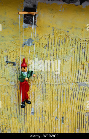 In legno antico pupett pinocchio su un grunge parete gialla. Le marionette giocattolo retrò. Foto Stock