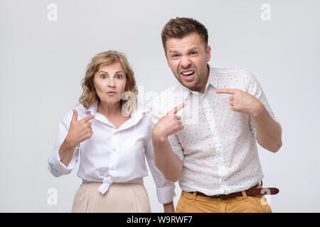 Donna e uomo chiedendo chi me essendo sconvolto interrogatorio dita di puntamento a se stesso Foto Stock