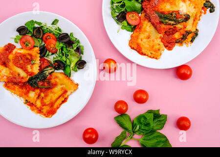 Lo stile italiano di Spinaci e Ricotta Ravioli pasto con olive nere eun insalata verde Foto Stock