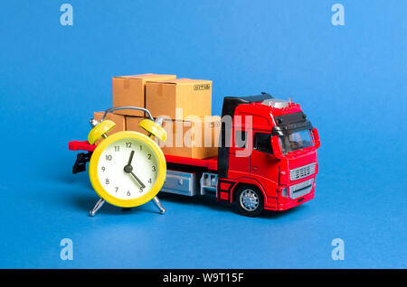 Un carrello con carico di scatole di cartone e un allarme giallo orologio. Express consegna in breve tempo concetto. La memorizzazione temporanea e limitata e convenienti. Op Foto Stock
