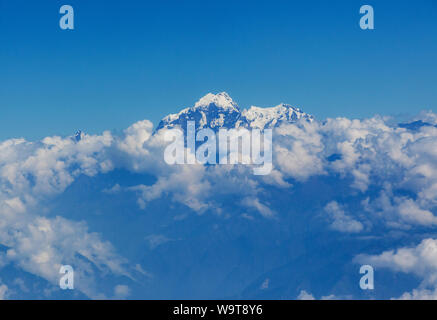 Vista aerea del Himalaya picchi di montagna sopra le nuvole sotto un cielo blu. Foto Stock