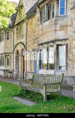 Vecchia panca in legno nella parte anteriore del Cotswold case di pietra in sheep street. Burford, Cotswolds, Oxfordshire, Inghilterra Foto Stock