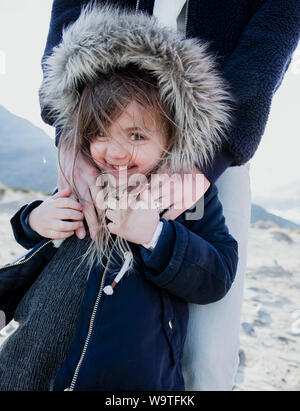 Ritratto di una madre che abbraccia la figlia che indossa una finta pelliccia giacca con cappuccio, Palm Springs, California, Stati Uniti Foto Stock
